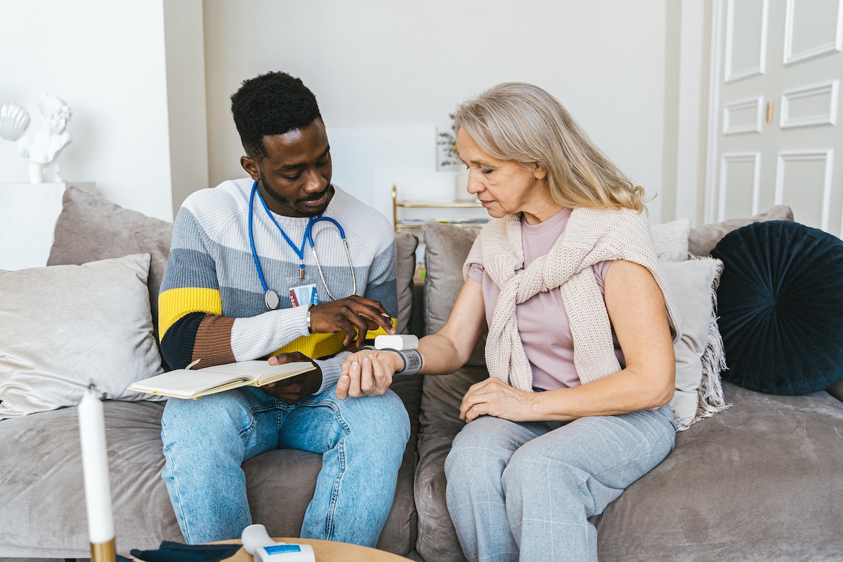 Male home healthcare nurse with older female patient