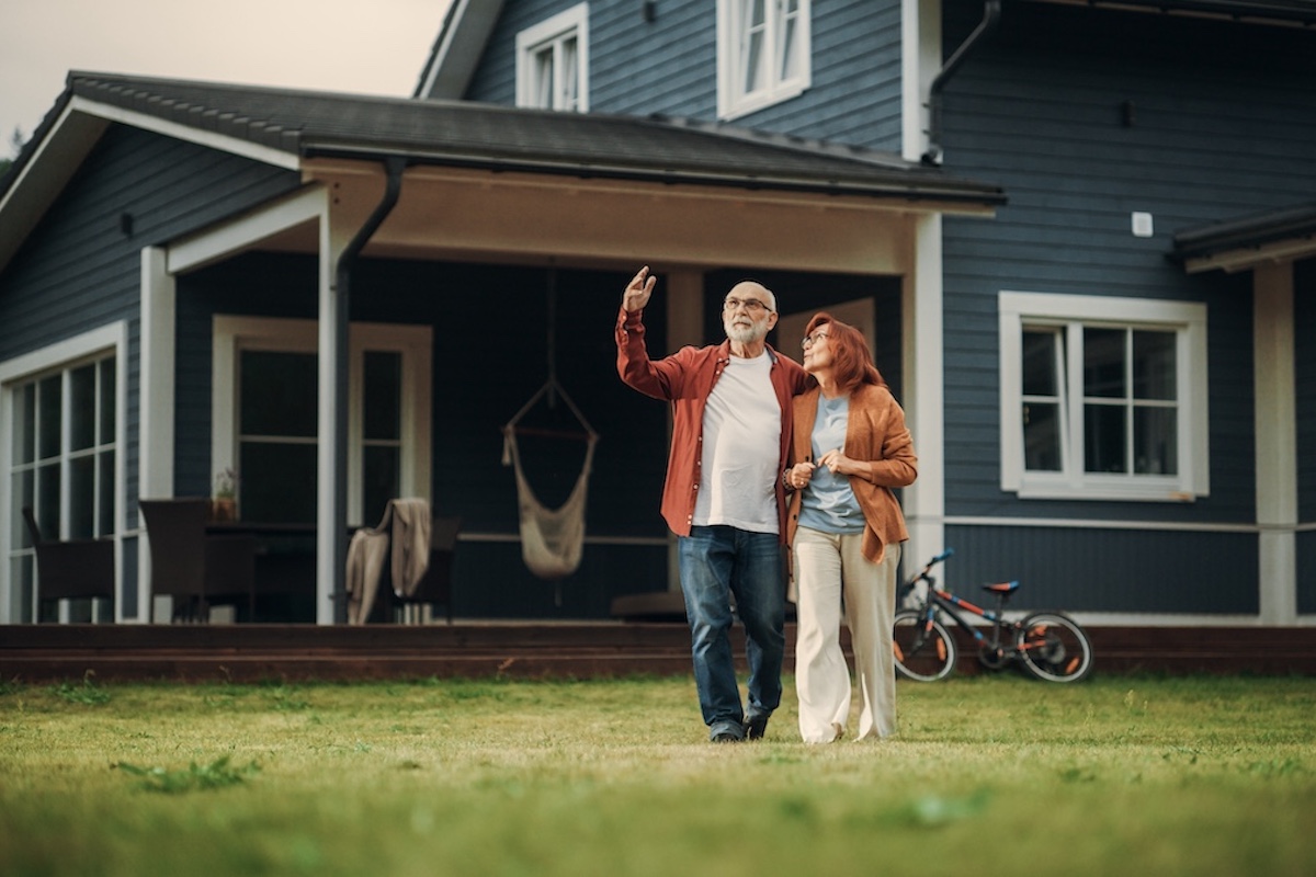 two people standing on the grass in front of their house